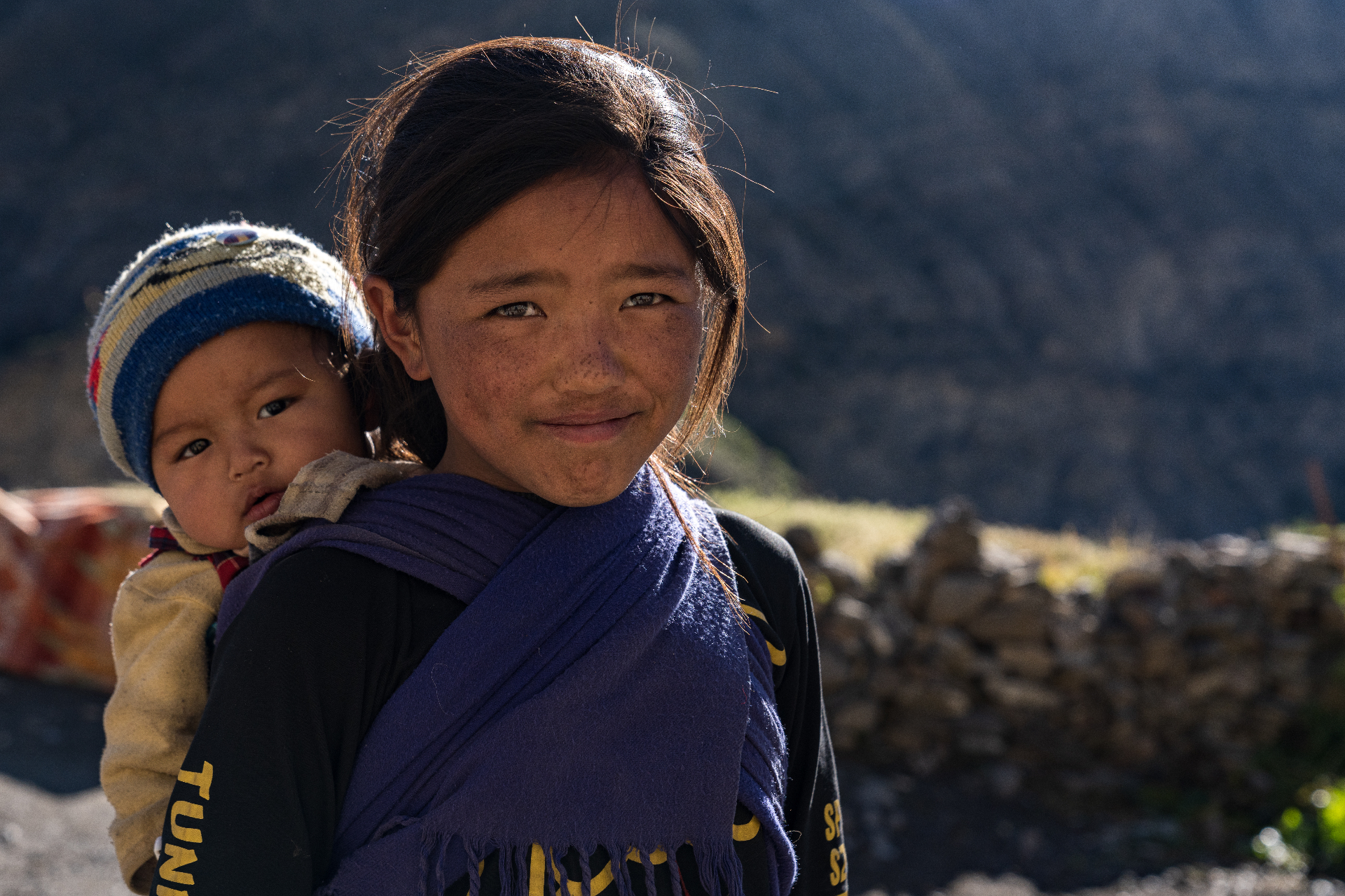 Portrait of a girl carrying a baby in rural Nepal